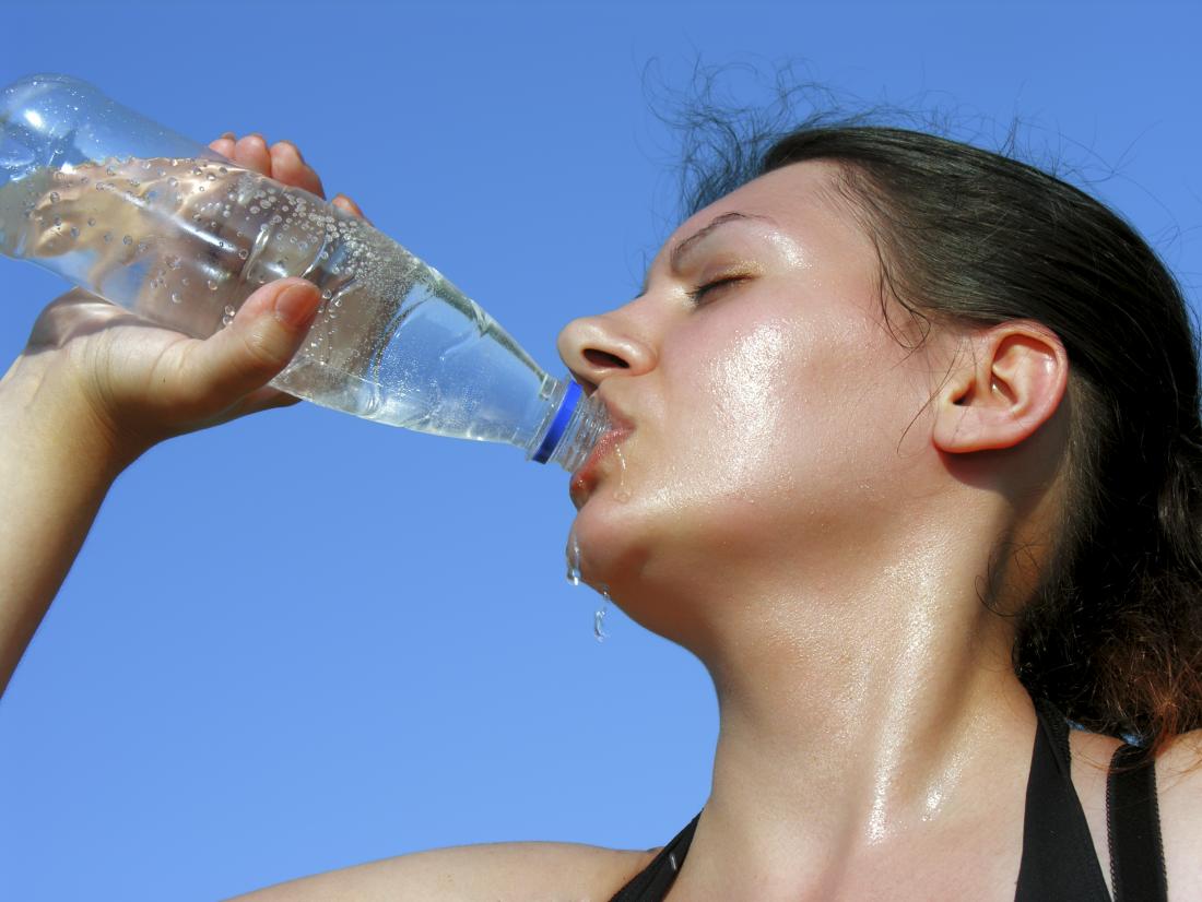 Woman drinking water on a hot day due to lightheadedness