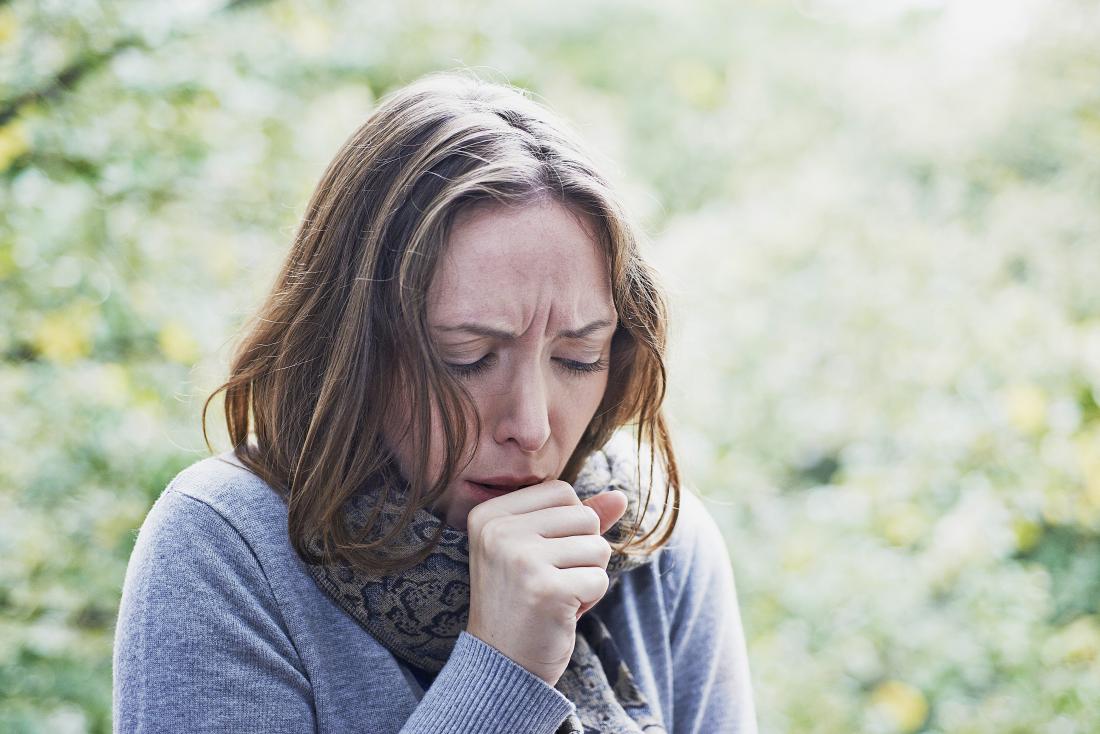 woman outdoors with flu or cold infection coughing