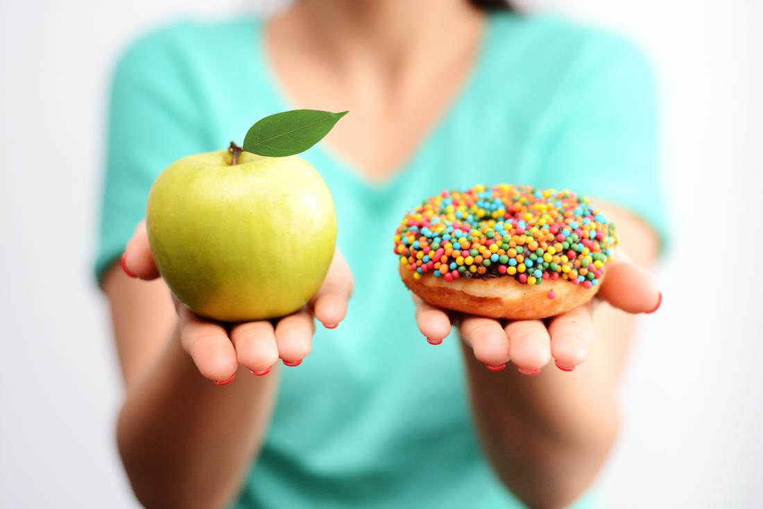 woman holding apple and donut