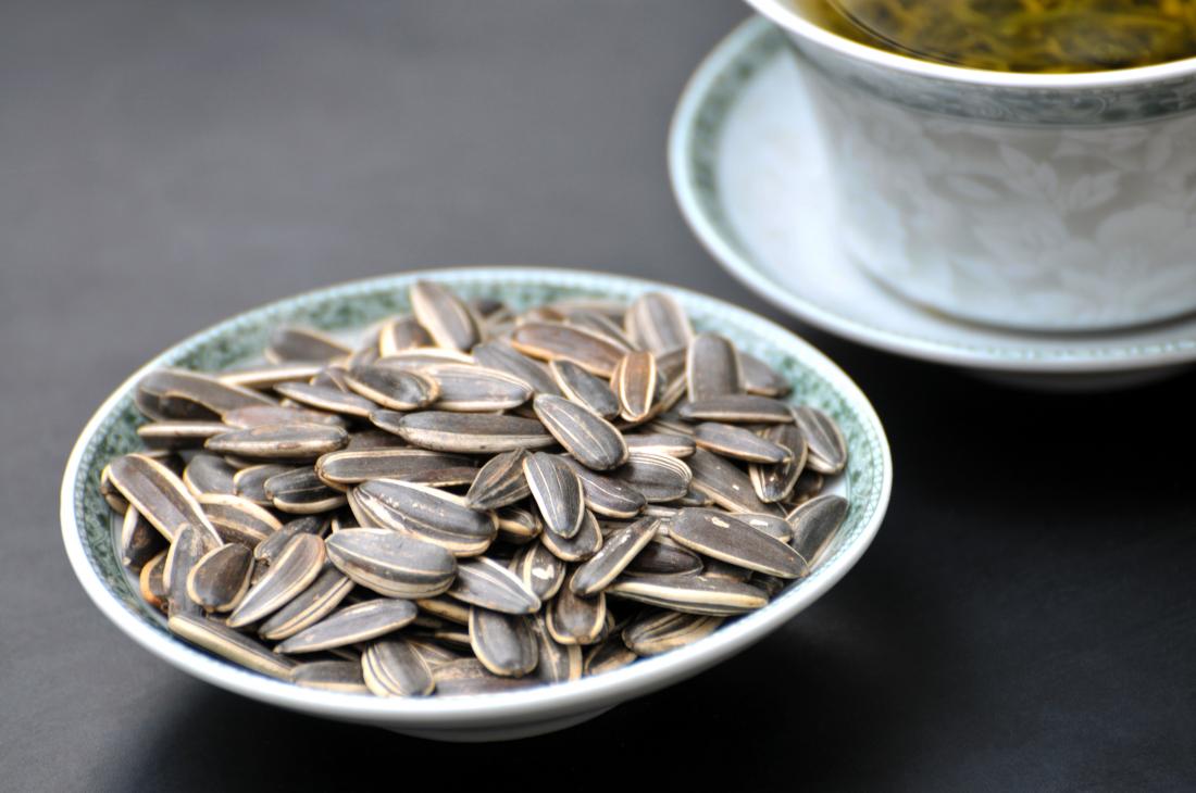 Sunflower seeds in bowl next to tea.