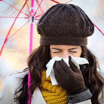 A woman with a cold blows her nose.