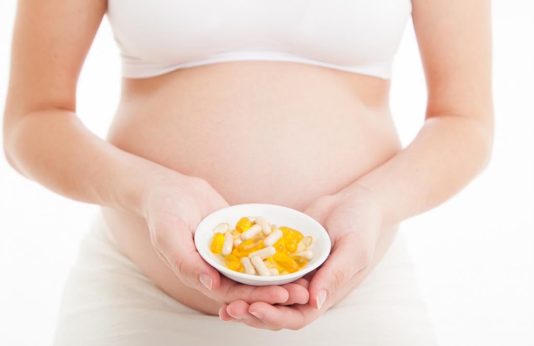 a pregnant woman holding multivitamins