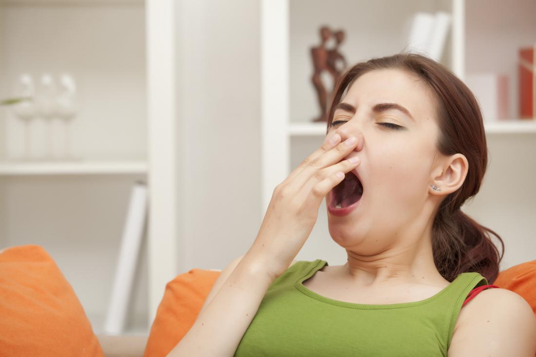 Woman at home yawning and covering her mouth.