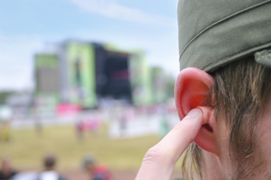 man at music festival using ear plugs