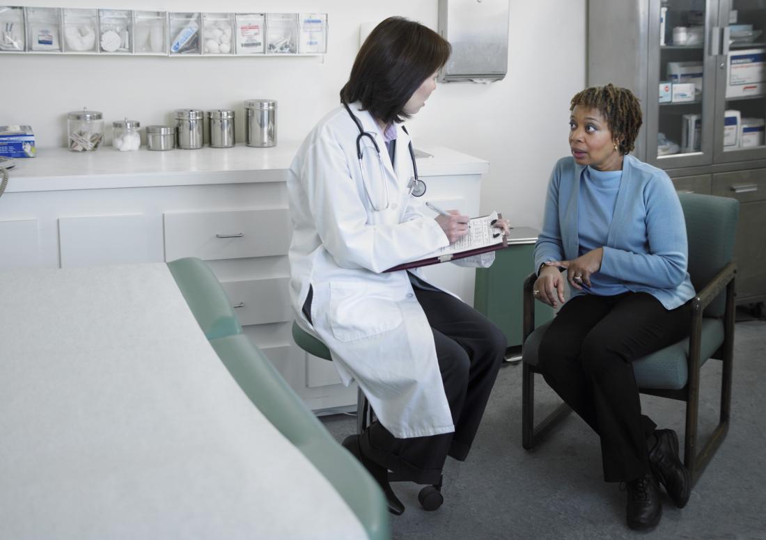 Mature female patient speaking to doctor in office.