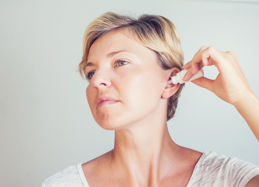 Woman using ear drops to remove built up ear wax