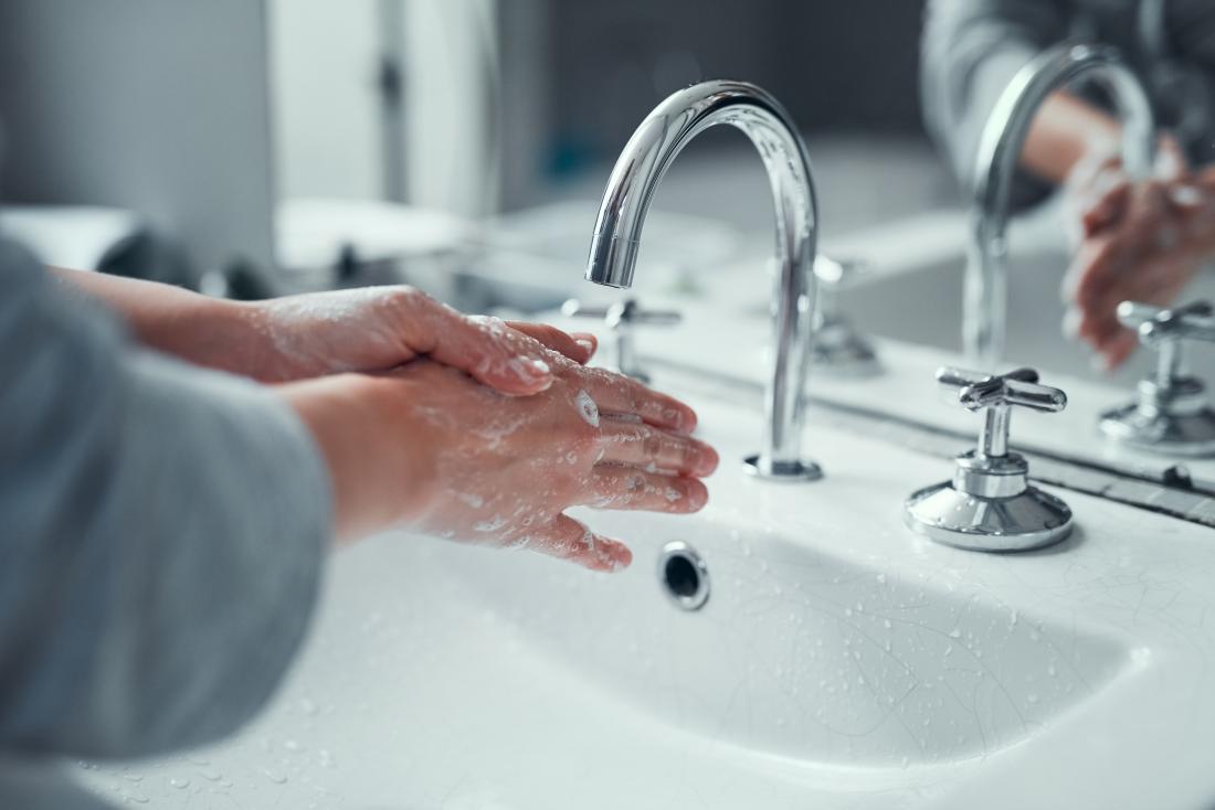 Person washing hands under running water from tap