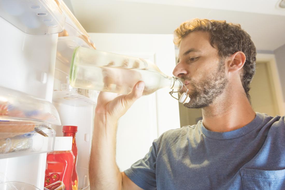 man drinking water from bottle in fridge
