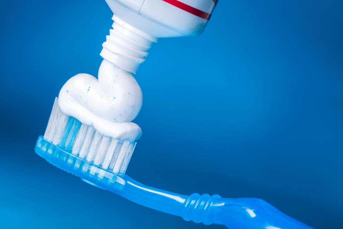 toothpaste being added to a toothbrush