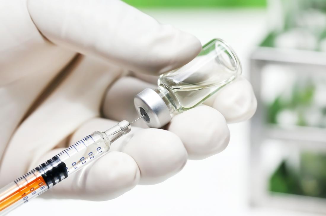 Vaccine shot being taken from bottle by syringe for injection