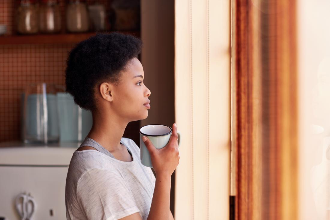 Woman with a mug looking out of window thoughtfully