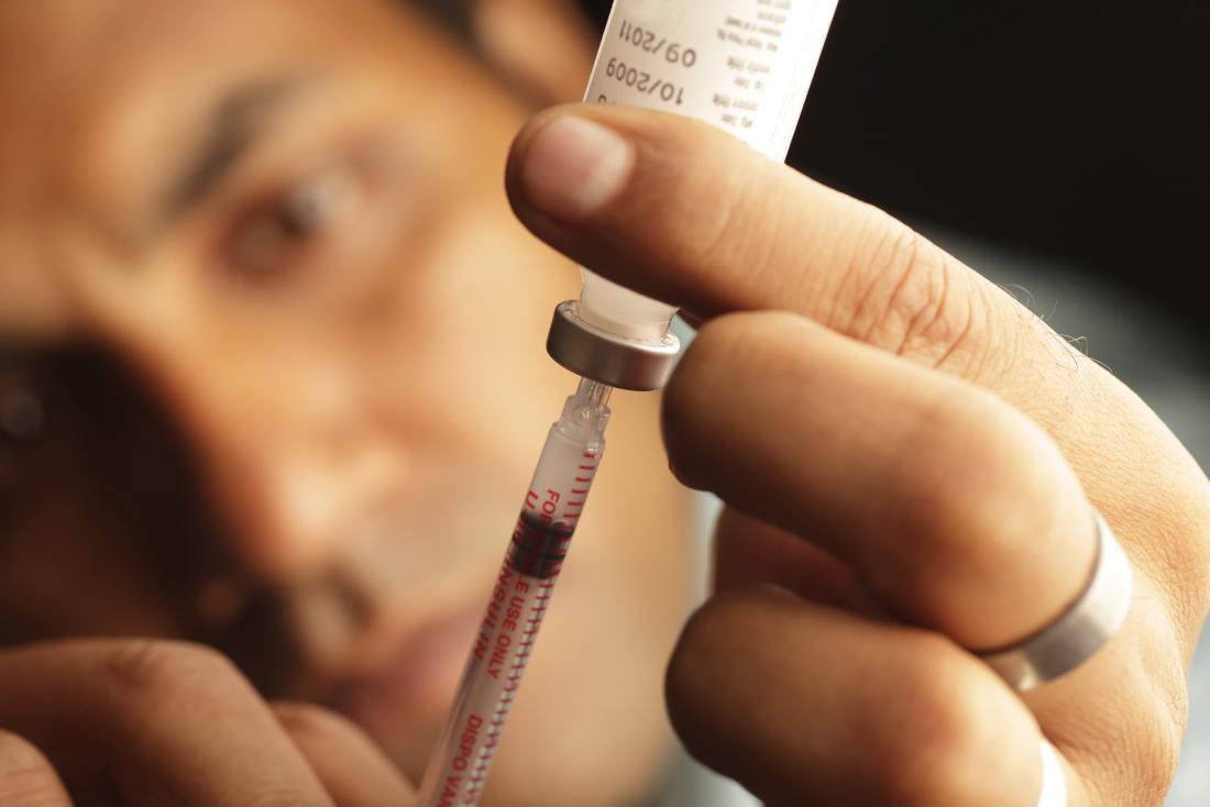 Person taking insulin from bottle into syringe