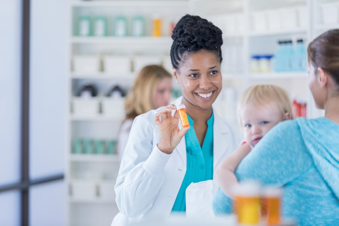 Pharmacist helping mother with toddler with prescription medication.