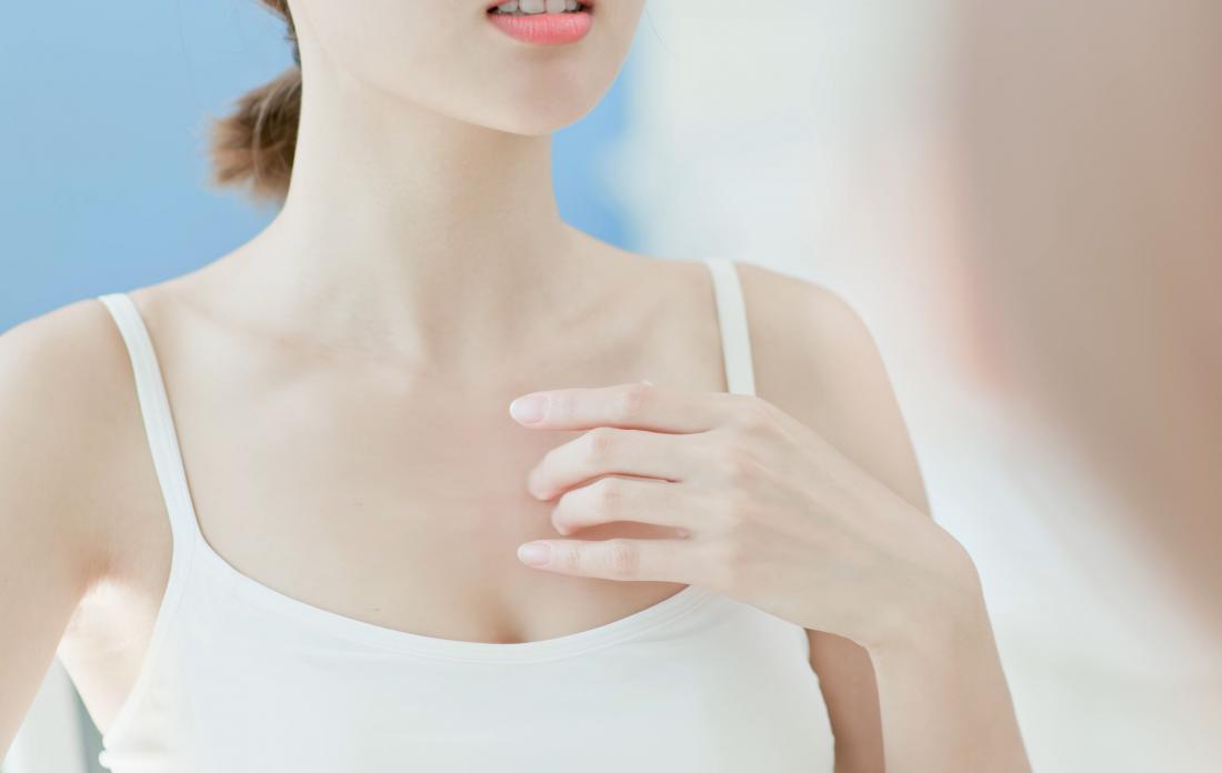 Woman looking in the mirror with hand on chest