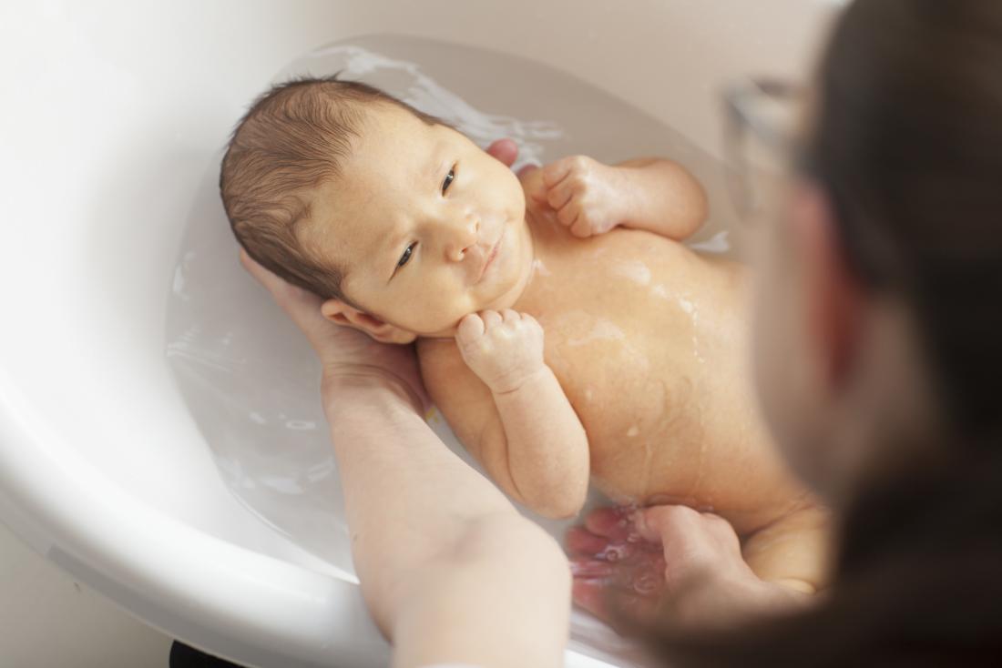 Person bathing baby in water