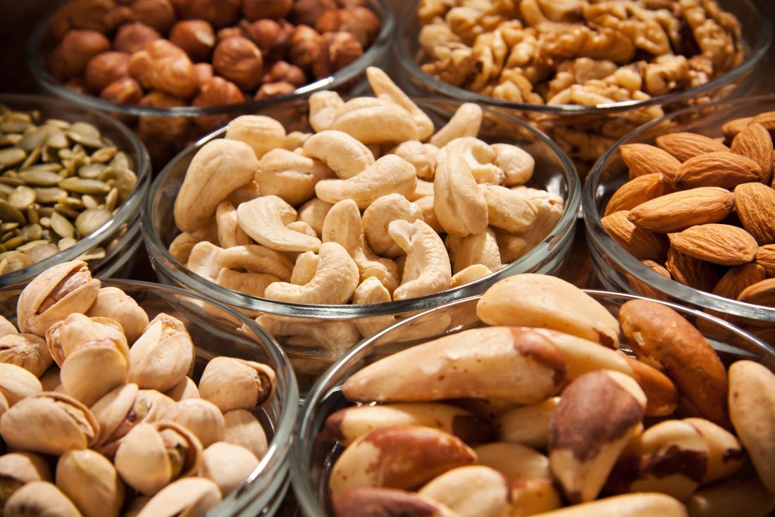 Nuts and seeds in bowls, including cashews, brazil nuts, sunflower seeds almonds, pistachios, hazelnuts, and walnuts.