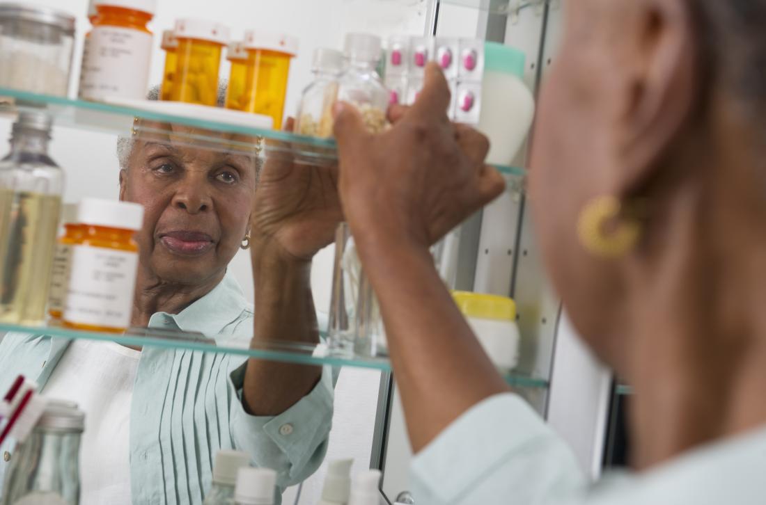 woman taking medicine from cabinet