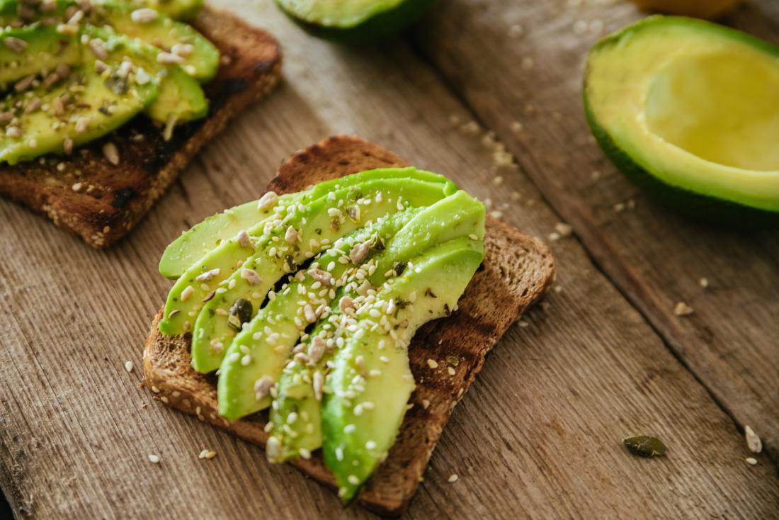 Avocado and seeds on toast on wooden table