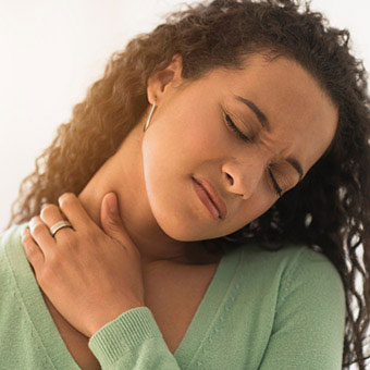 A woman rubs her sore neck due to a pinched nerve.