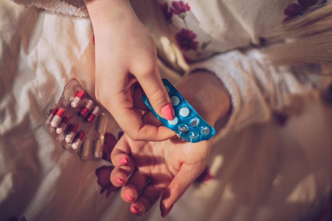 woman's hands taking sleeping pills