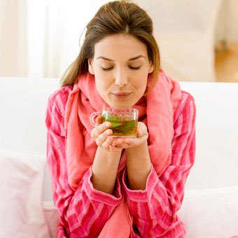 A woman in her pajamas drinking tea.
