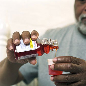 A man take cough medication (antitussives) to reduce the cough of his upper respiratory infection.