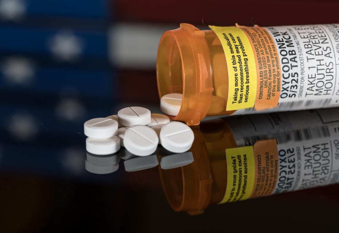 oxycodone tablet pills spilling out of prescription opioid bottle.