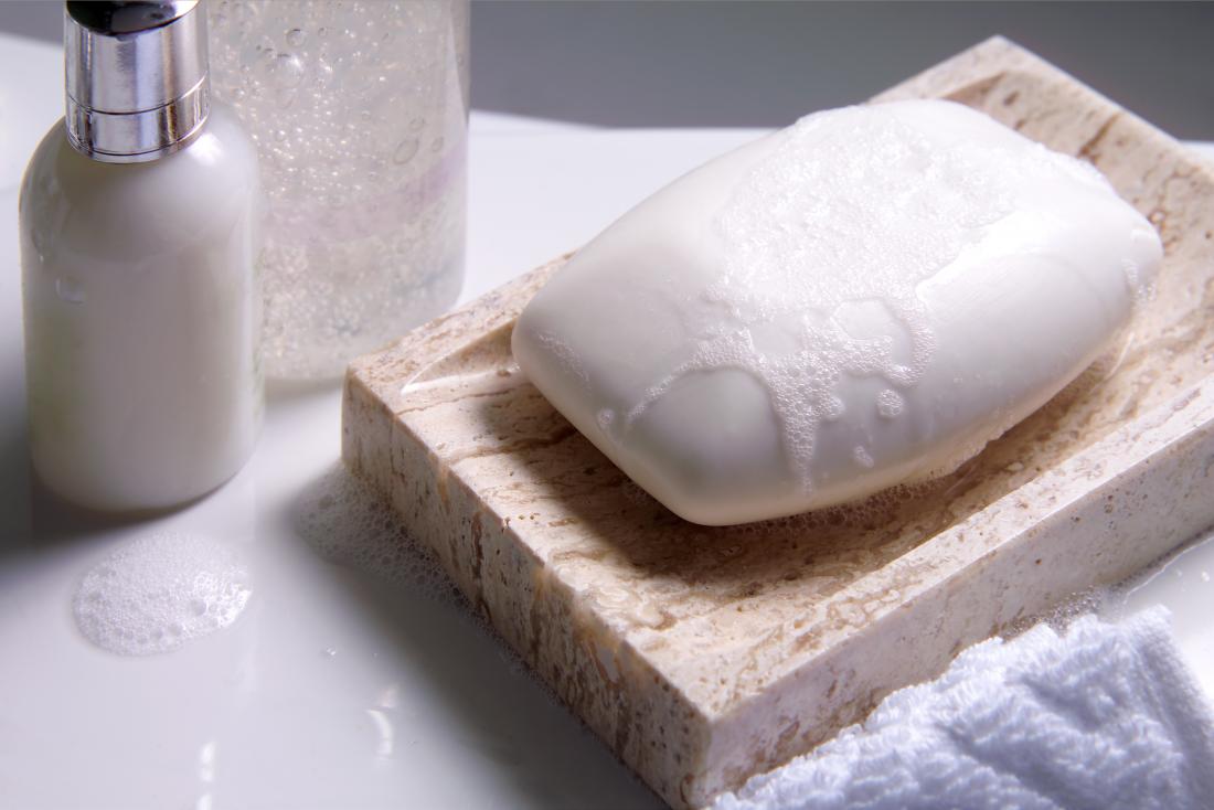 Soap bar in a wooden dish next to lotion