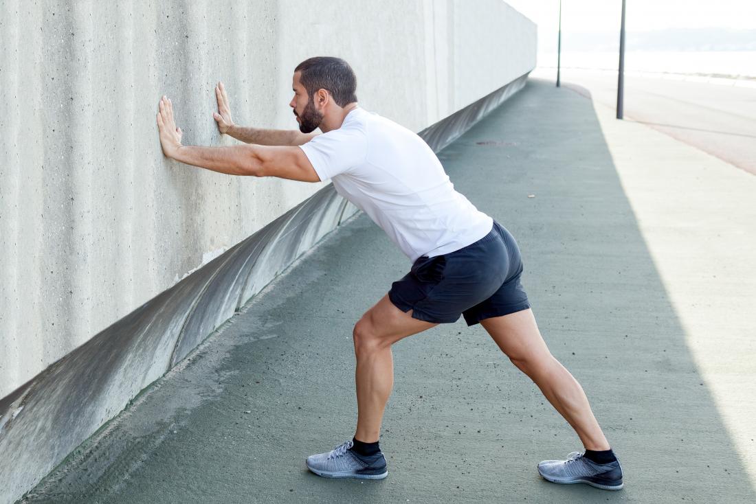 Man doing calf muscle and foot stretch against wall