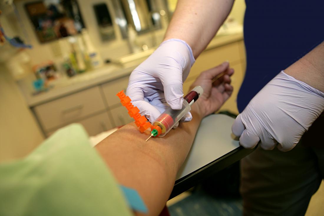 Phlebotomist drawing blood for test from patient's arm