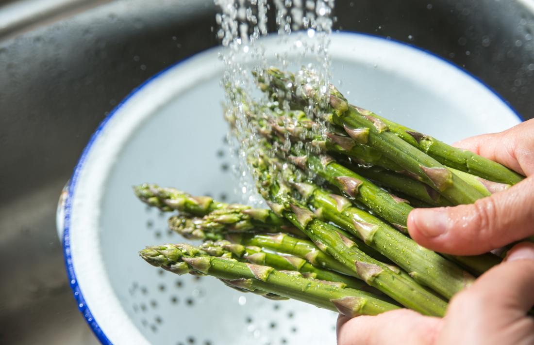 Asparagus being washed under a tap