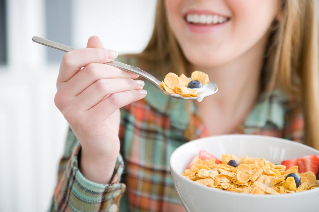 young woman eating cereal with fruit