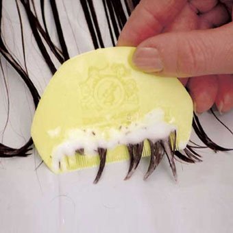 A lice comb is used to comb out dead lice, which can be seen in the medication foam.