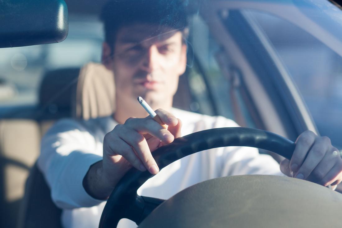 Man smoking cigarette while driving car