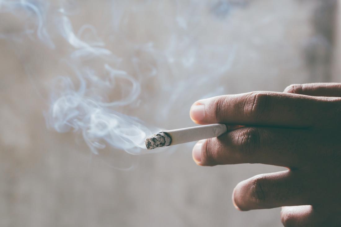 Smoking cigarette being held in person's hand linked to asthma