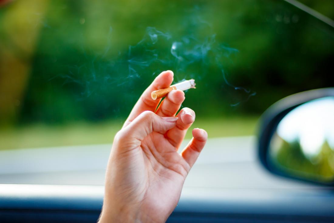 Woman smoking a cigarette in her car 