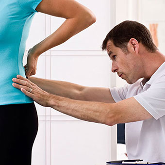 A doctor examines a patient's lower back.