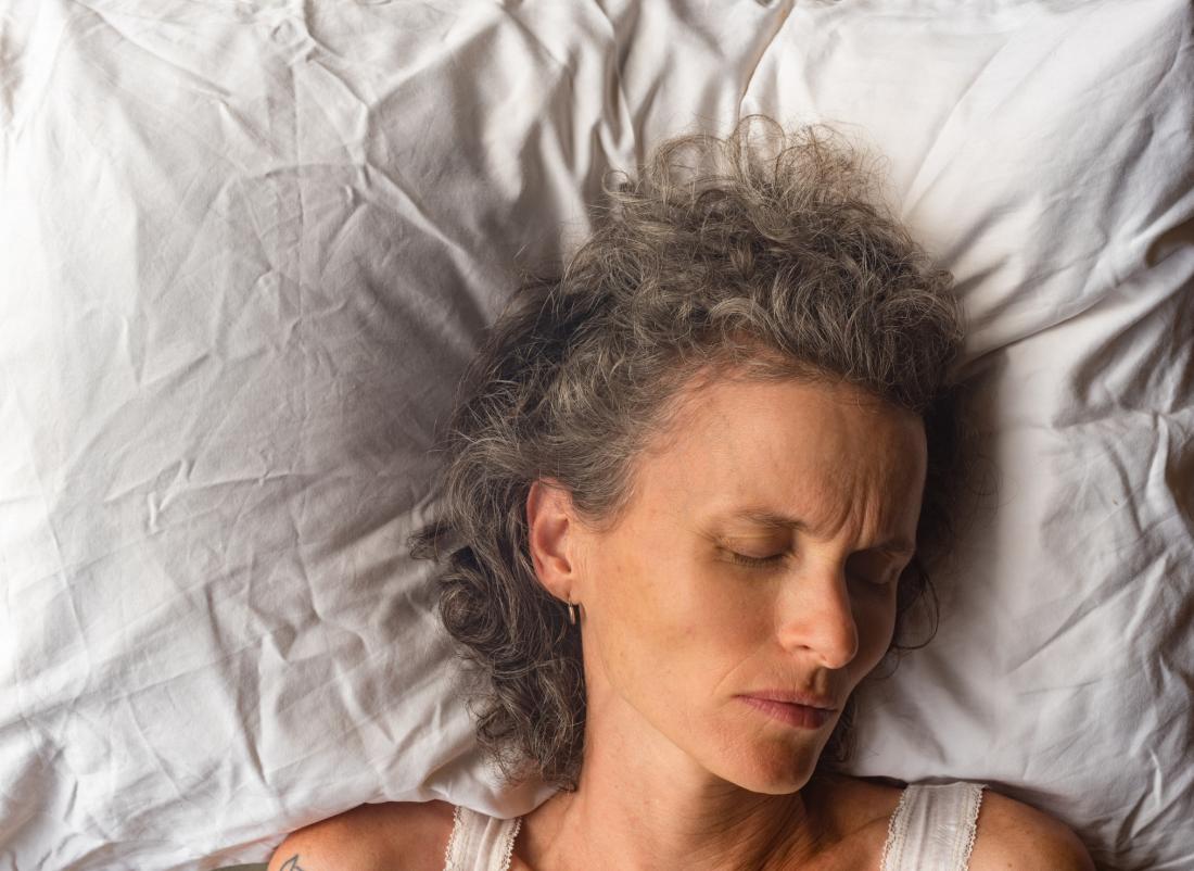 close up of grey haired woman asleep on white pillow