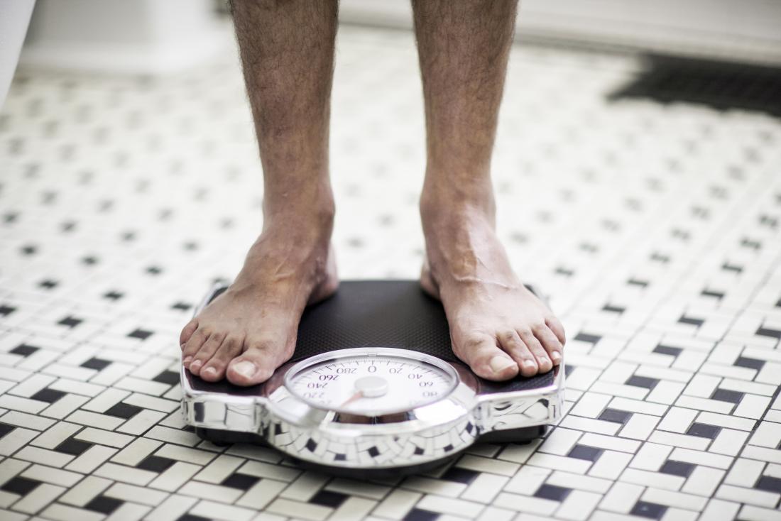Male feet standing on scales to check for weight loss alongside blood in the urine.