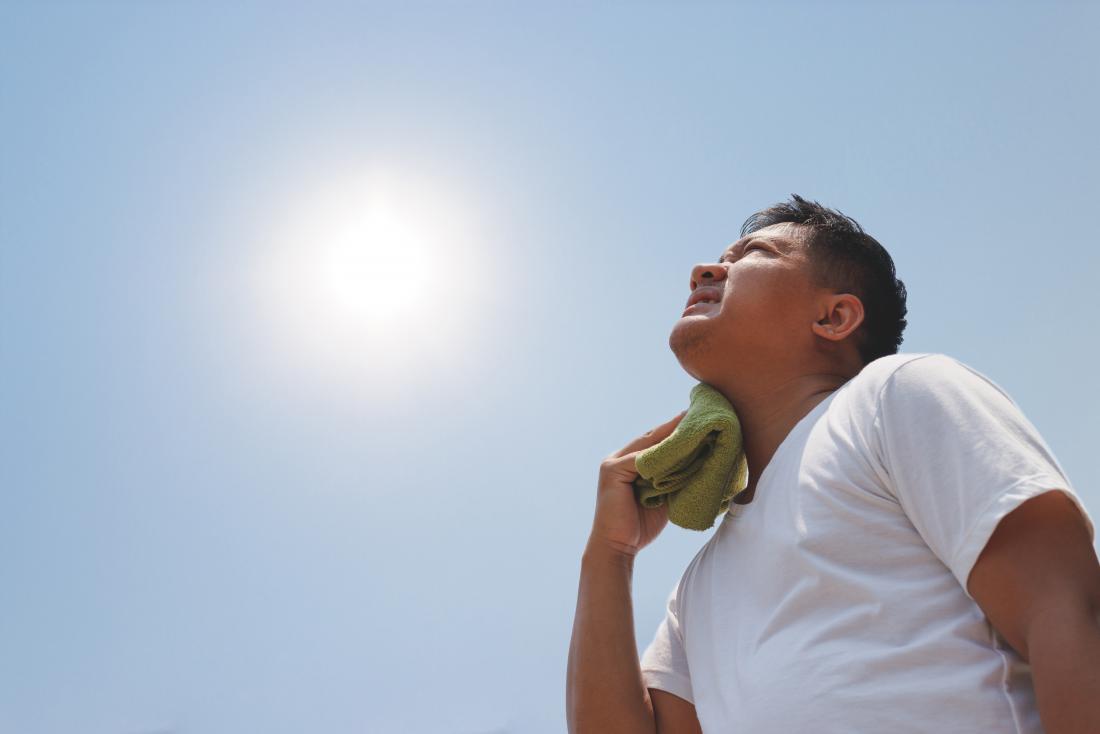 man in the sun holding wet cloth to neck