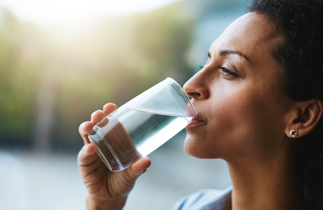 Woman drinking water due to dehydration which causes brown urine