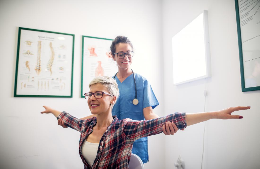 Woman having physical therapy stretching arms with doctor