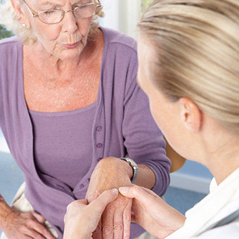 A patient feels joint tenderness as a doctor examines her hand for rheumatoid arthritis (RA).