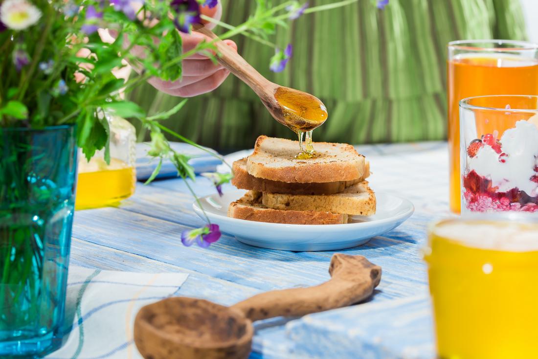 woman pouring honey on to toast