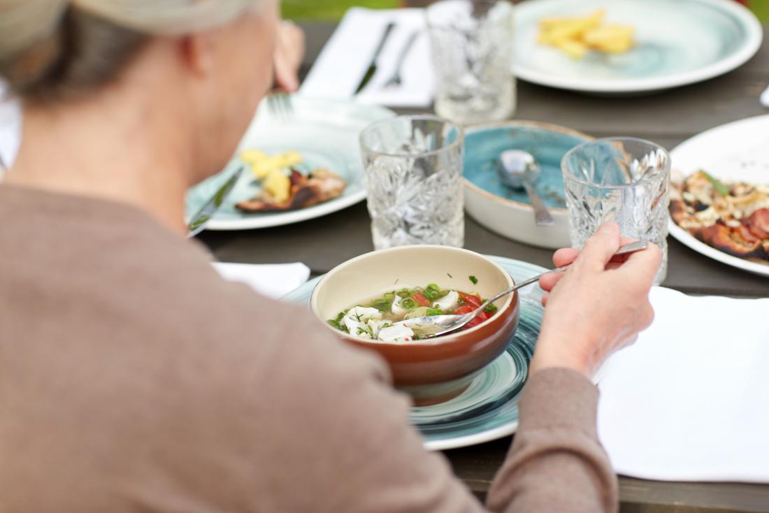 Woman eating small soup meal outdoors