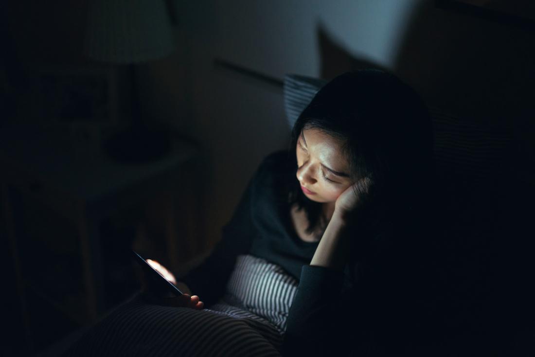 sleepless person looking at phone in bed