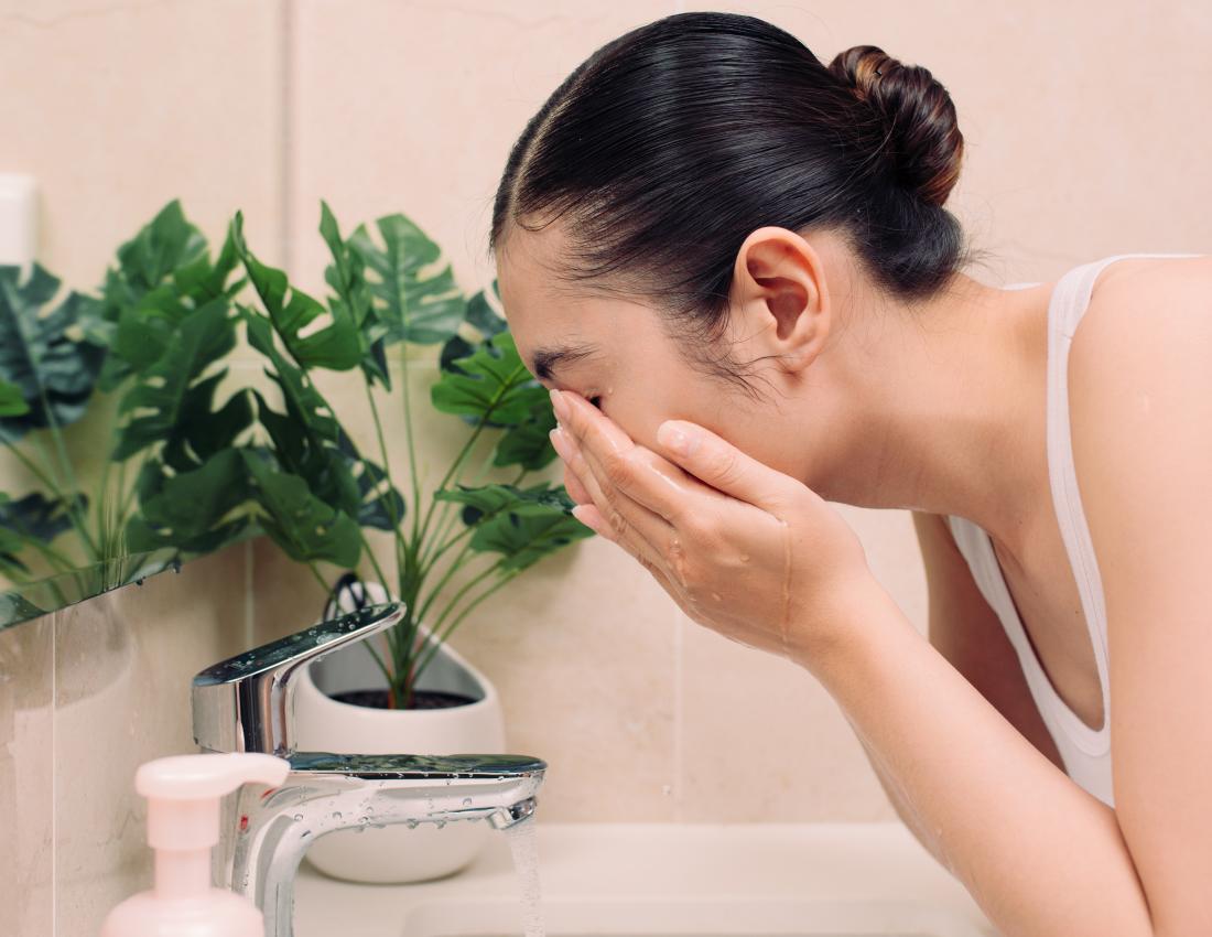 Woman washing her face with an exfoliator for dry skin on face