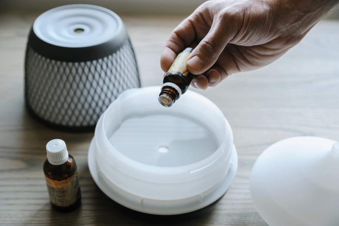 Person putting essential oil into aromatherapy diffuser