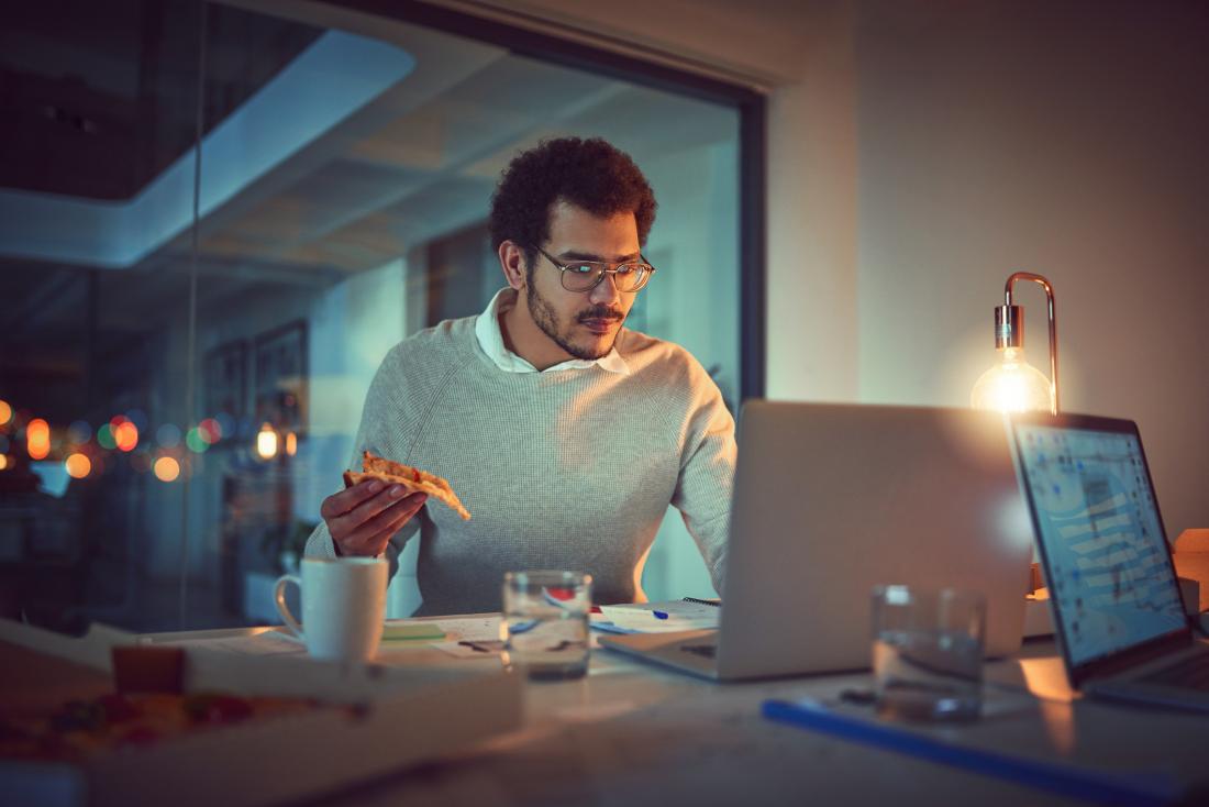 man eating pizza while working