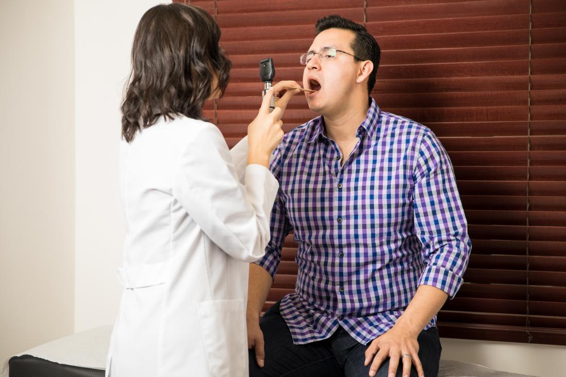 female doctor examining male patients throat